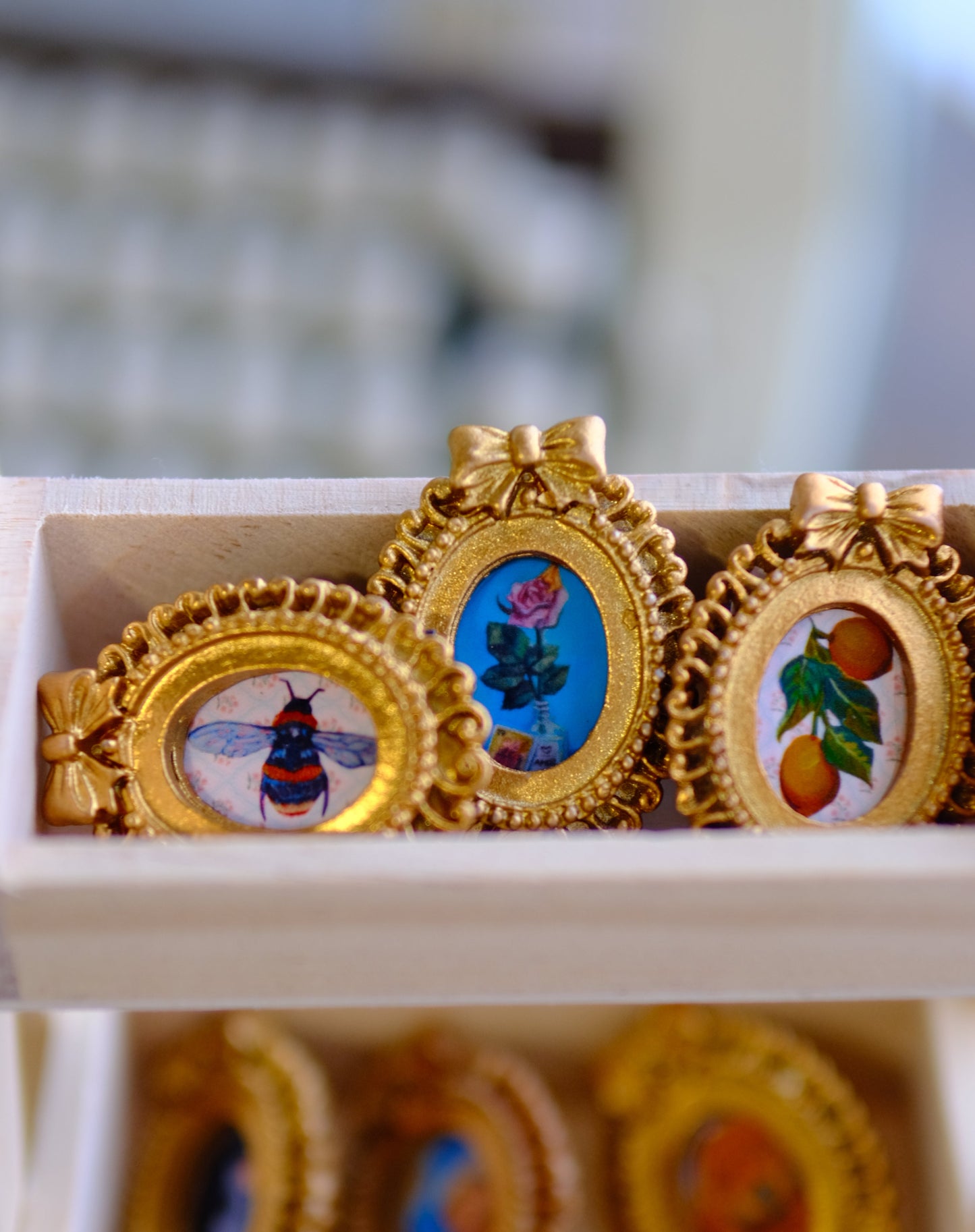 Decorative items with gold frames featuring illustrations on a white surface.