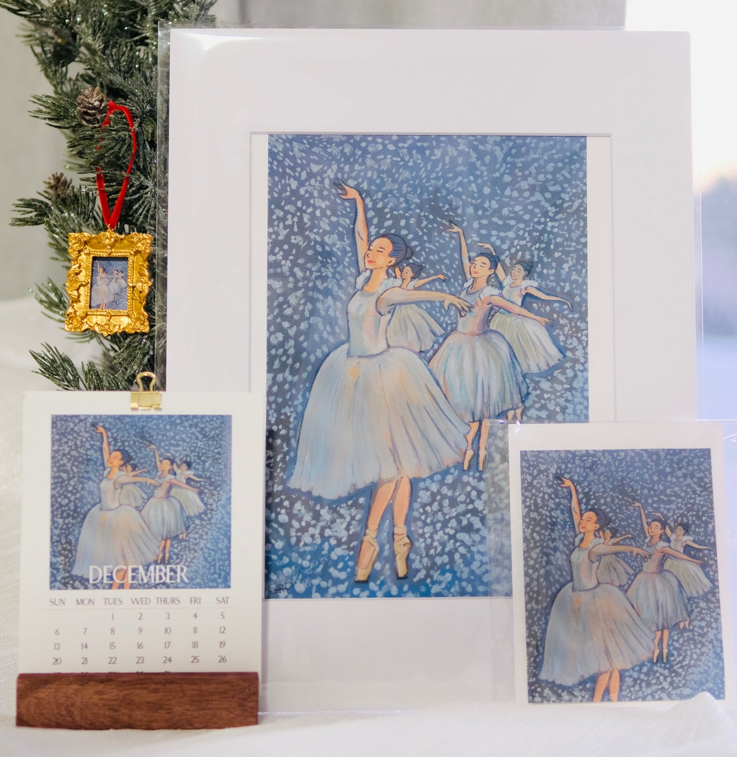 Framed ballet-themed calendar with decorative elements on a surface.