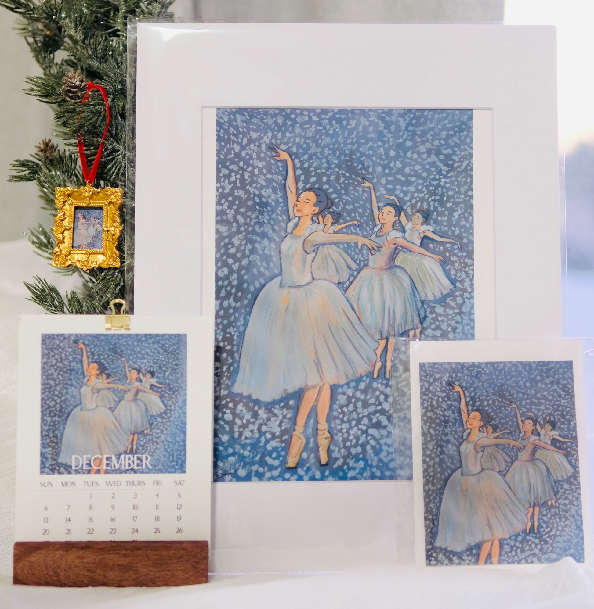 Framed ballet-themed calendar with decorative elements on a surface.